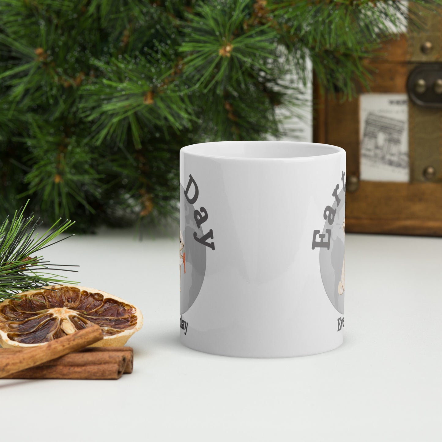 White ceramic mug with Earth Day Everyday Rabbit Ceramic Mug design near pine branches and dried citrus