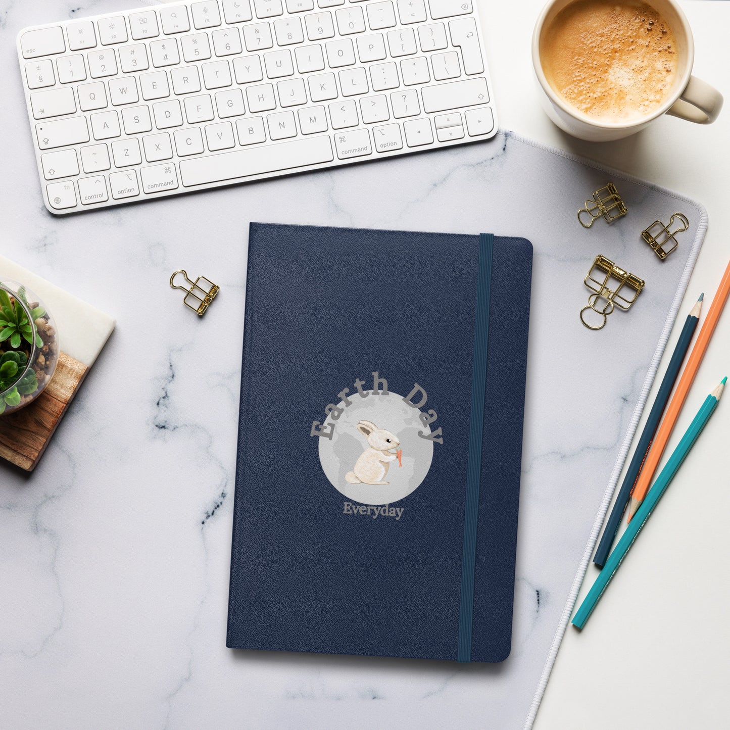 Earth Day Everyday Rabbit Hardcover Bound Notebook by VivaTrek placed on marble desk next to keyboard coffee and pencils