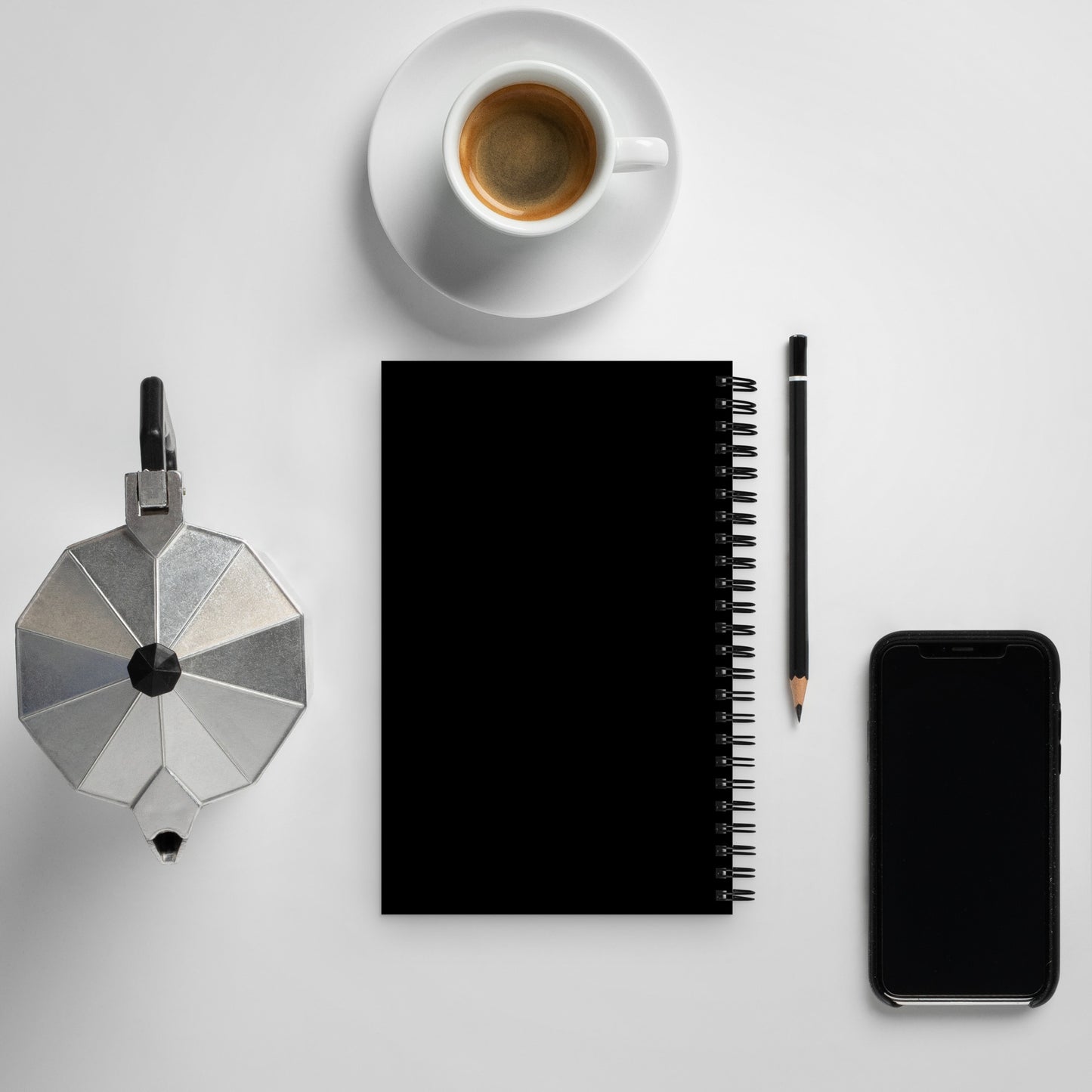 Earth Day Everyday Rabbit Spiral Notebook with black cover next to coffee cup, pencil, phone, and stovetop espresso maker