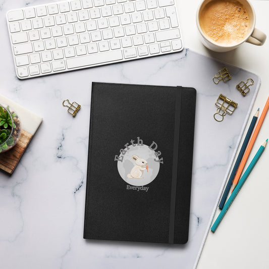Earth Day Everyday Rabbit Hardcover Bound Notebook with black cover featuring rabbit design on a marble desk