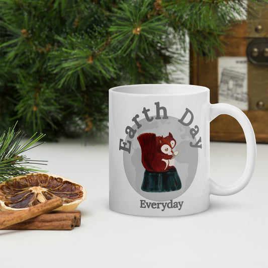 White Earth Day Everyday Squirrels Ceramic Mug with squirrel graphic on table next to pine leaves and dried citrus